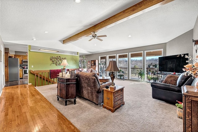 living room featuring ceiling fan, a textured ceiling, light carpet, and vaulted ceiling with beams