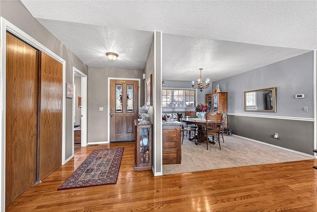 entrance foyer with vaulted ceiling, a chandelier, hardwood / wood-style floors, and a textured ceiling