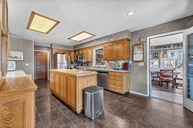 kitchen with sink, stainless steel appliances, a center island, and a textured ceiling