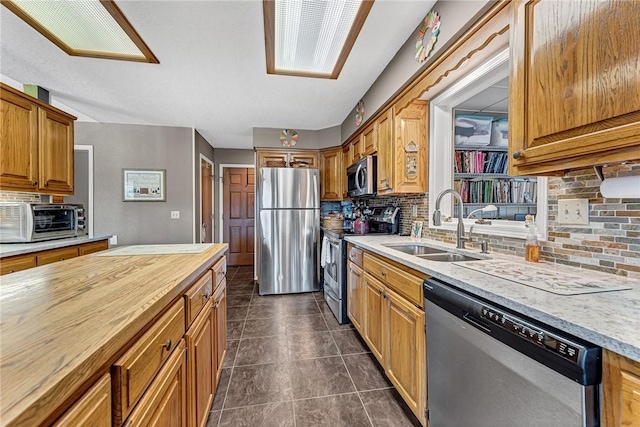 kitchen with dark tile patterned floors, appliances with stainless steel finishes, sink, backsplash, and butcher block countertops