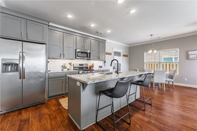 kitchen with appliances with stainless steel finishes, sink, gray cabinets, a breakfast bar, and a center island with sink