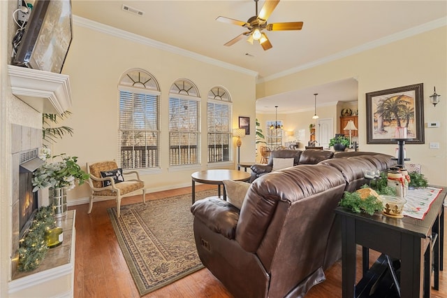 living room featuring a premium fireplace, hardwood / wood-style flooring, ceiling fan, and crown molding