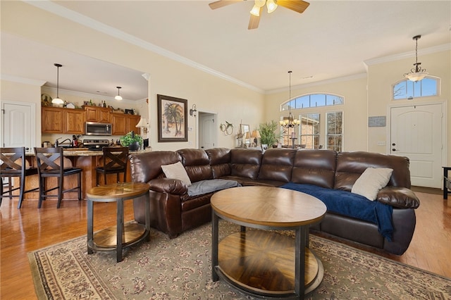 living room with ceiling fan with notable chandelier, crown molding, and wood-type flooring