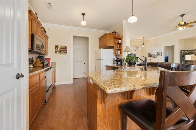 kitchen with dark hardwood / wood-style floors, hanging light fixtures, sink, stainless steel appliances, and a breakfast bar area