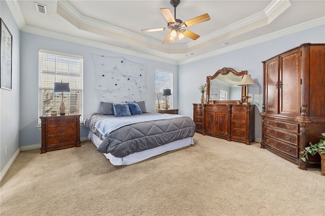 bedroom with ceiling fan, light carpet, a tray ceiling, and crown molding