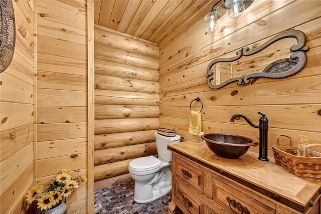 bathroom with toilet, vanity, log walls, and wood ceiling