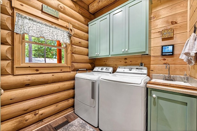 laundry area featuring cabinets, rustic walls, sink, and independent washer and dryer