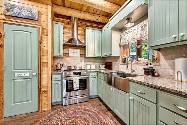 kitchen with wood ceiling, stainless steel range, wall chimney range hood, beamed ceiling, and sink