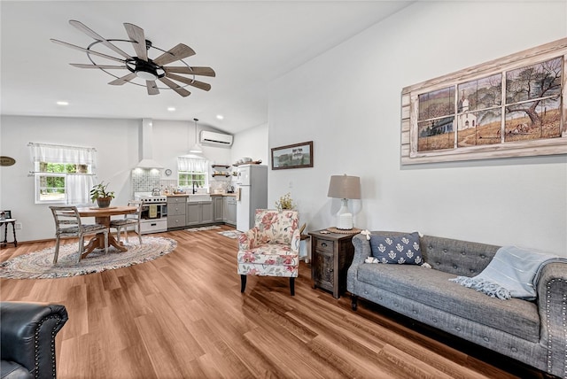 living room featuring a wall unit AC, ceiling fan, sink, hardwood / wood-style floors, and lofted ceiling