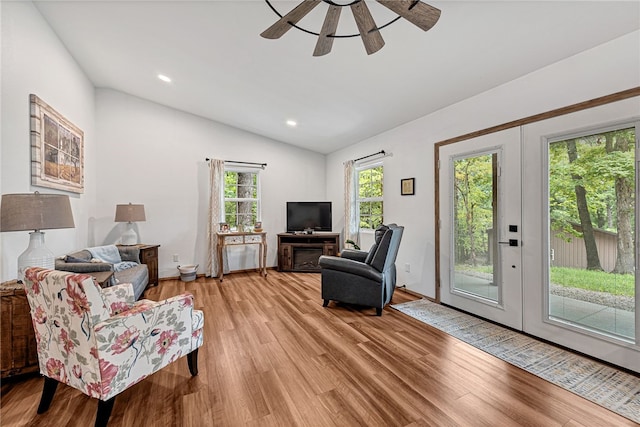 living room with light wood-type flooring, vaulted ceiling, ceiling fan, and french doors