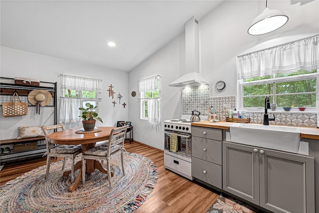 kitchen with wall chimney exhaust hood, backsplash, gray cabinets, lofted ceiling, and white electric range