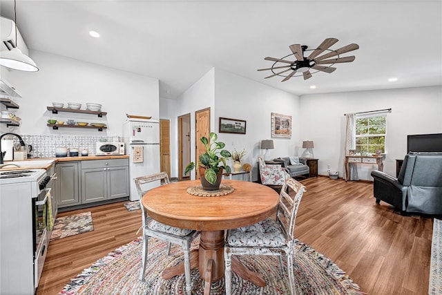 dining room with light wood-type flooring, vaulted ceiling, ceiling fan, and sink