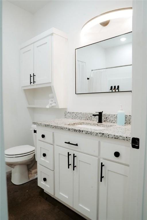 bathroom featuring concrete floors, toilet, a shower with shower curtain, and vanity