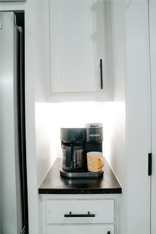 bar featuring white cabinets and stainless steel fridge