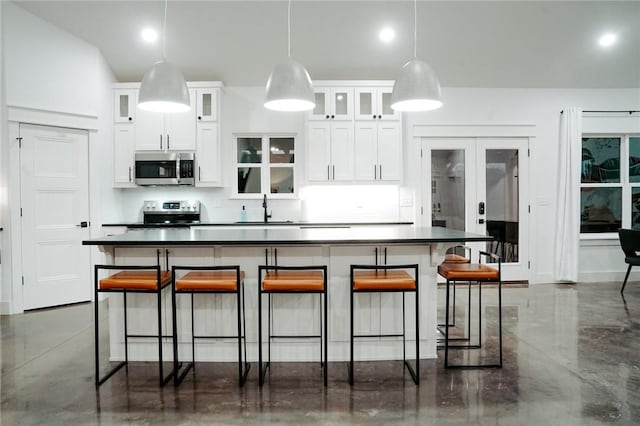 kitchen with hanging light fixtures, french doors, white cabinetry, a breakfast bar area, and stainless steel appliances