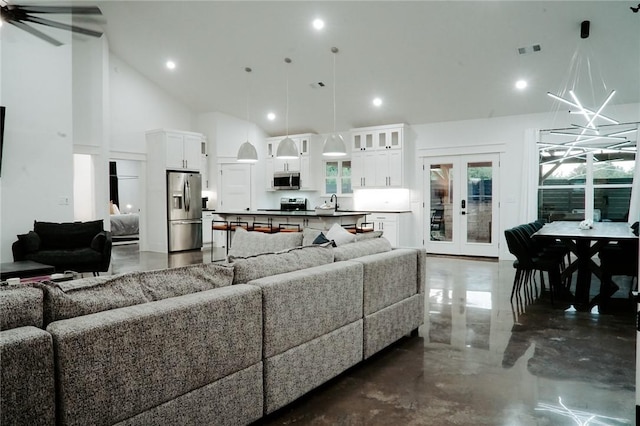 living room featuring high vaulted ceiling, french doors, and an inviting chandelier