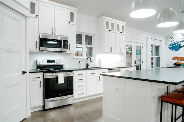 kitchen with a kitchen breakfast bar, appliances with stainless steel finishes, sink, white cabinetry, and a kitchen island