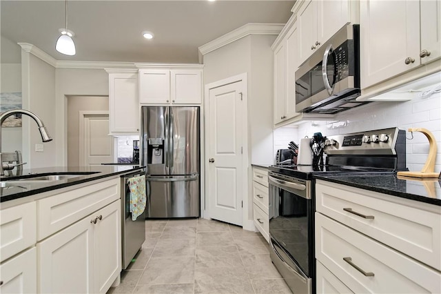 kitchen with appliances with stainless steel finishes, hanging light fixtures, white cabinets, ornamental molding, and sink