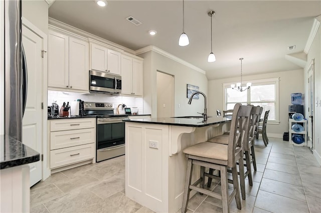 kitchen featuring decorative light fixtures, stainless steel appliances, a kitchen island with sink, and sink