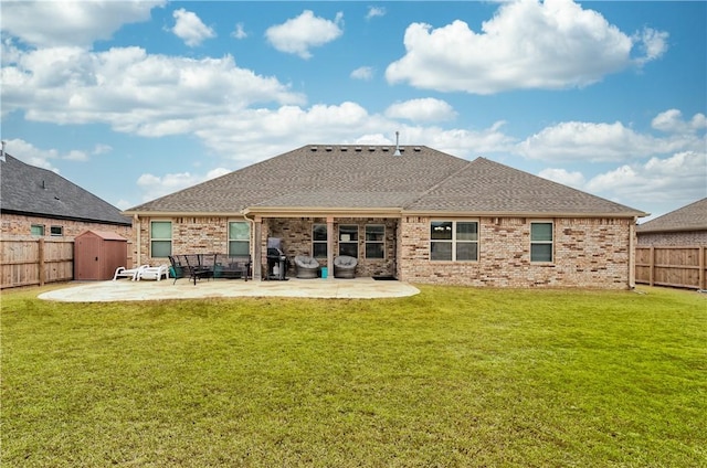 back of property with a patio, a yard, and a storage shed