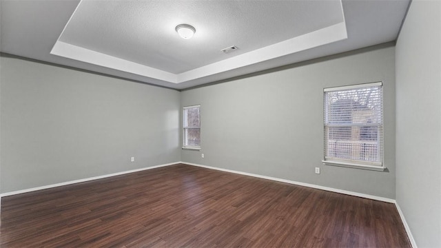 spare room featuring dark hardwood / wood-style floors and a tray ceiling