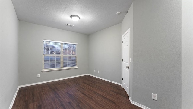 spare room featuring dark hardwood / wood-style flooring and a textured ceiling