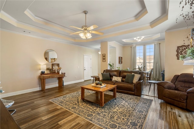 living room featuring a raised ceiling, crown molding, and dark wood-type flooring