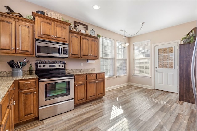 kitchen featuring light stone countertops, light hardwood / wood-style flooring, and stainless steel appliances