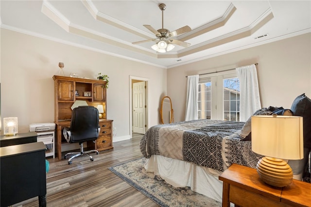 bedroom with ceiling fan, ornamental molding, dark hardwood / wood-style floors, and a tray ceiling