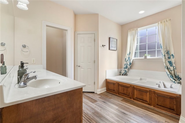 bathroom featuring hardwood / wood-style floors, a bath, and vanity