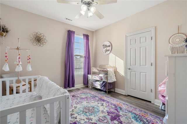 bedroom featuring hardwood / wood-style flooring, ceiling fan, and a nursery area