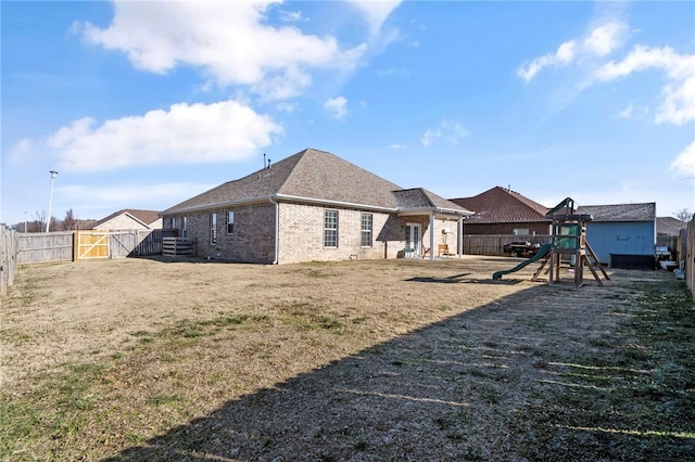 rear view of house with a playground and a yard