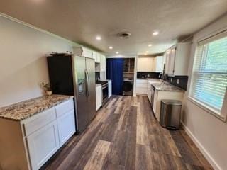 kitchen featuring stainless steel refrigerator with ice dispenser, washer / dryer, dark wood-type flooring, white cabinetry, and light stone counters