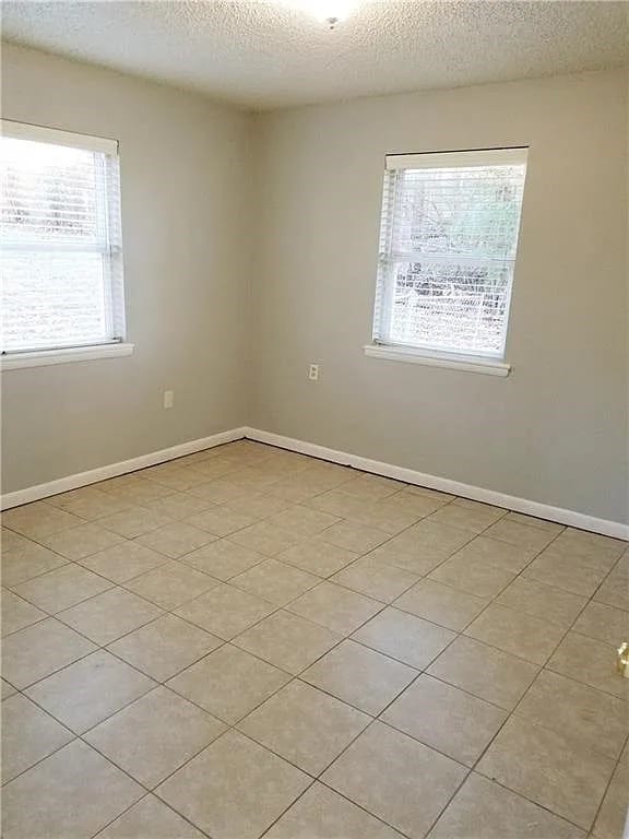 tiled empty room with a textured ceiling