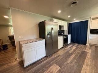 kitchen with white cabinets, stainless steel appliances, light stone counters, and dark wood-type flooring