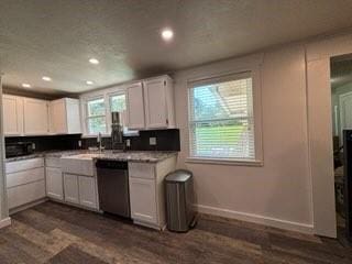 kitchen with stainless steel dishwasher, white cabinetry, a wealth of natural light, and dark hardwood / wood-style flooring