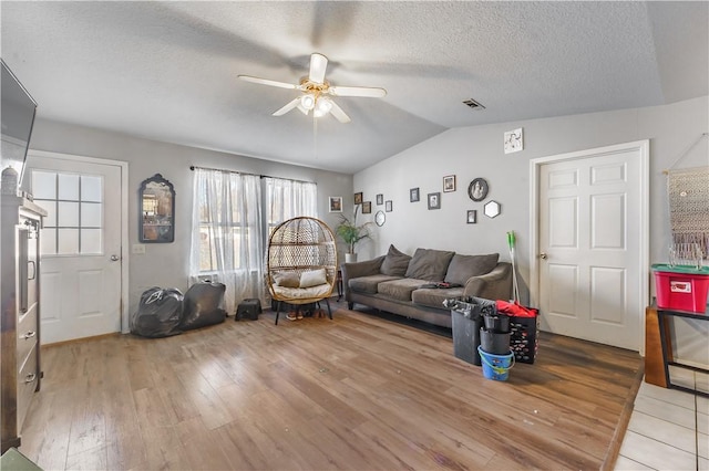 living room featuring ceiling fan, wood-type flooring, lofted ceiling, and a textured ceiling