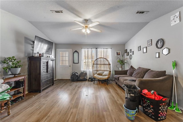 living room featuring ceiling fan, a textured ceiling, light hardwood / wood-style flooring, and lofted ceiling