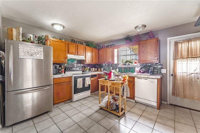 kitchen with sink, white appliances, a textured ceiling, and decorative backsplash