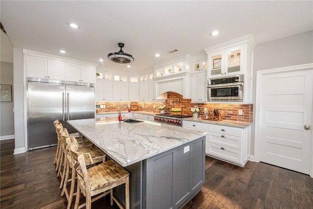 kitchen featuring white cabinetry, an island with sink, sink, and premium appliances