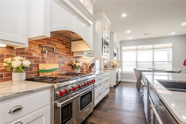 kitchen featuring white cabinetry, decorative backsplash, light stone counters, stainless steel appliances, and dark wood-type flooring