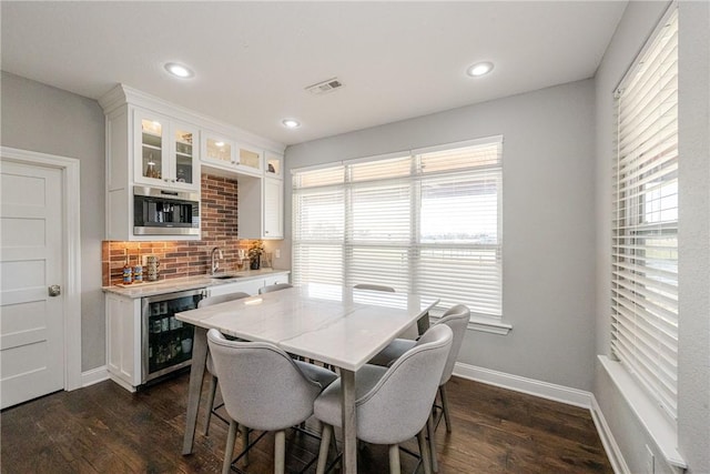 dining area with dark hardwood / wood-style floors, bar, and beverage cooler