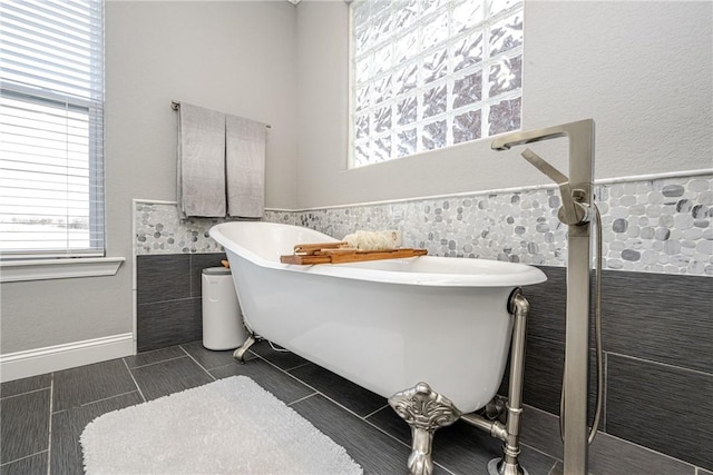 bathroom with tile patterned flooring, a bathing tub, and tile walls