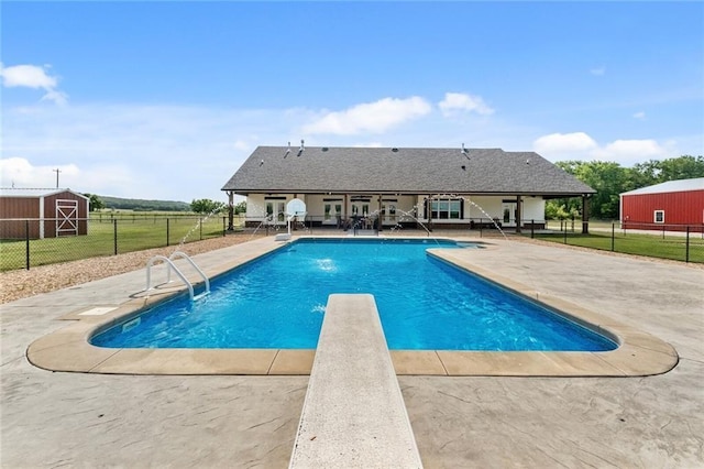 view of swimming pool featuring a shed, a patio, and a diving board