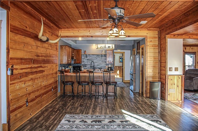 kitchen with wood walls, a kitchen bar, kitchen peninsula, and wooden ceiling