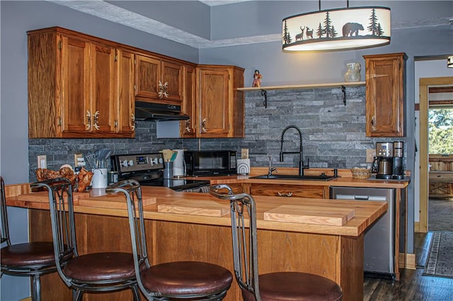 kitchen with pendant lighting, sink, stainless steel appliances, tasteful backsplash, and wood counters