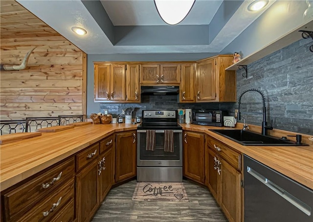 kitchen featuring extractor fan, sink, wooden counters, black appliances, and a raised ceiling