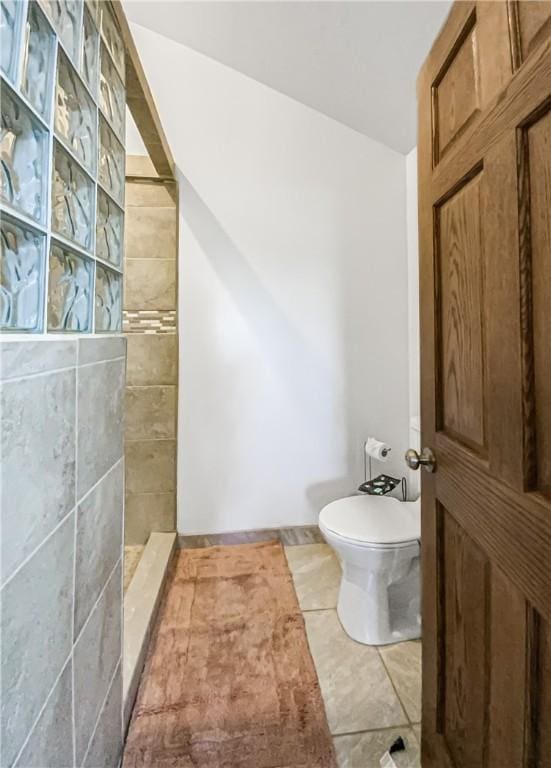 bathroom with a tile shower and toilet