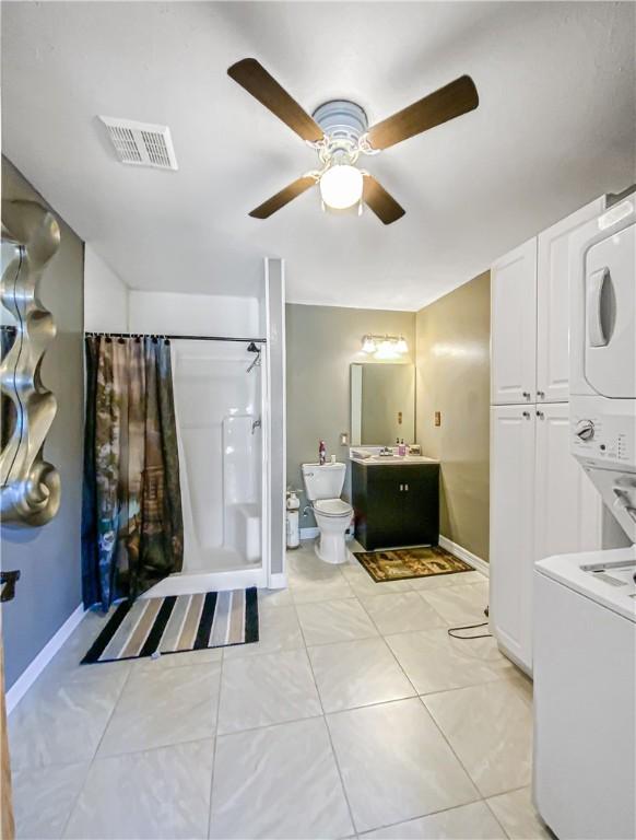 bathroom with stacked washer and dryer, vanity, tile patterned flooring, and walk in shower