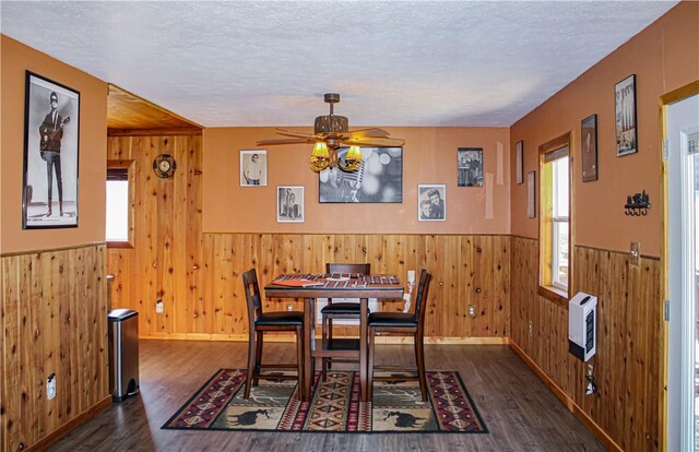 dining space with dark wood-type flooring, ceiling fan, heating unit, and a textured ceiling